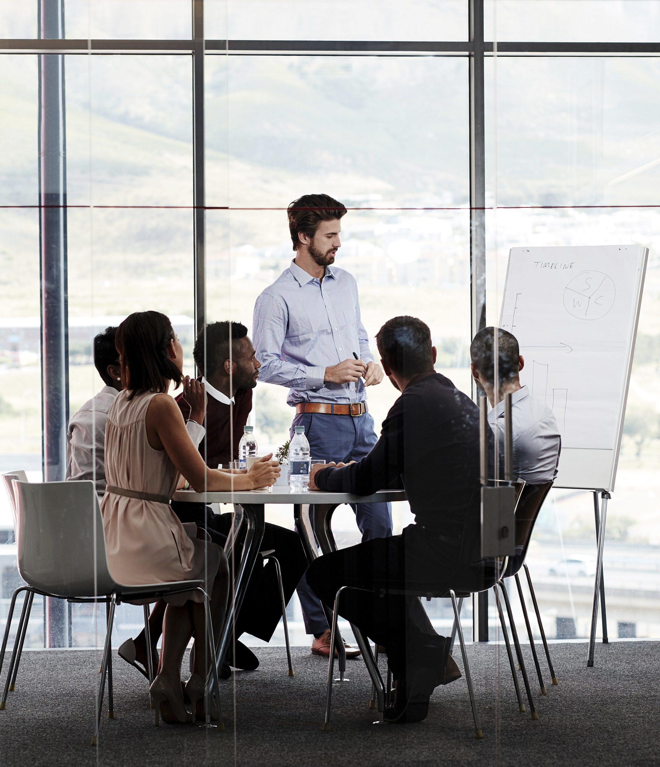 Presenter A coach conducting a meeting with six people sitting around a table.