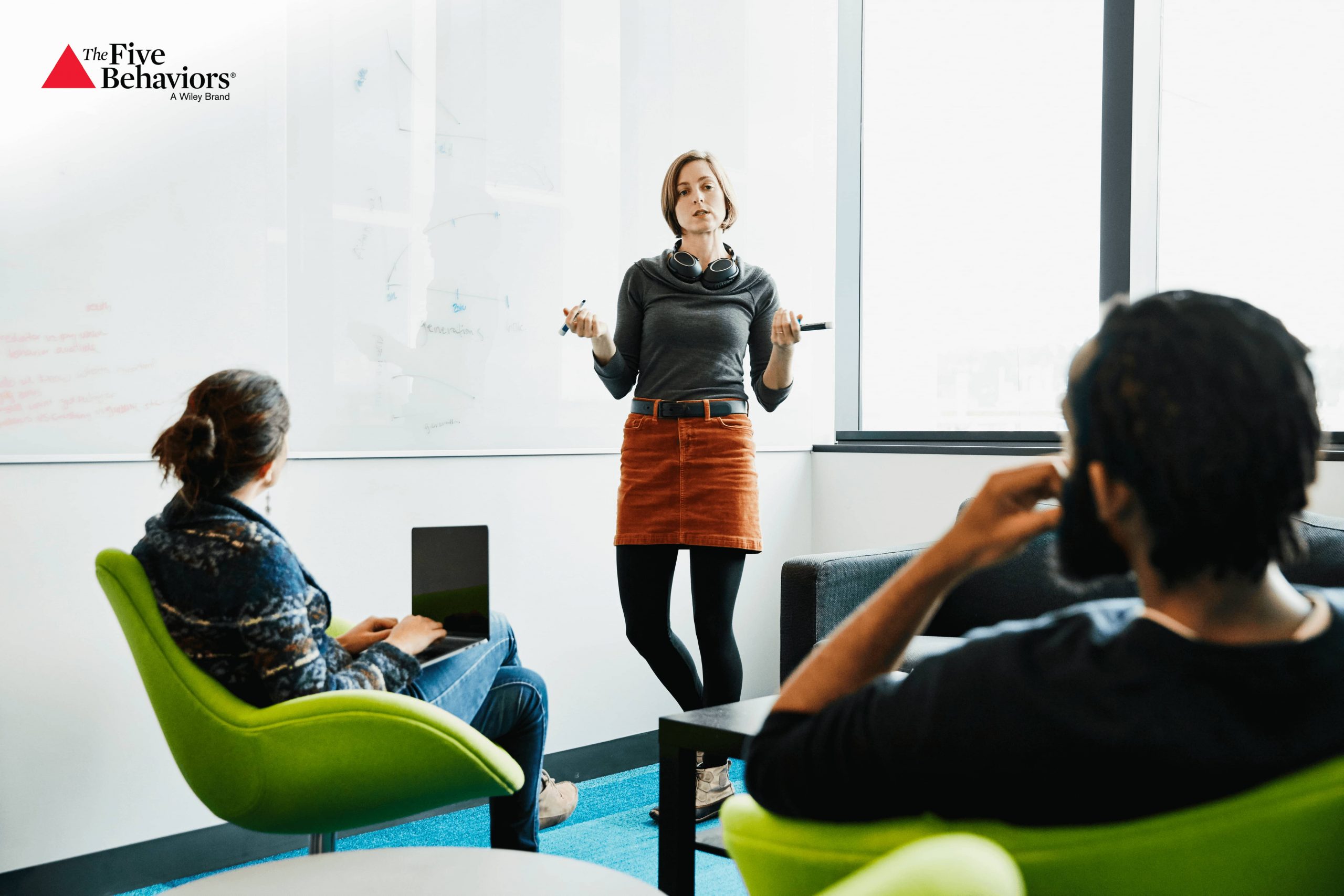 Women standing in front of a whiteboard presenting to two people.